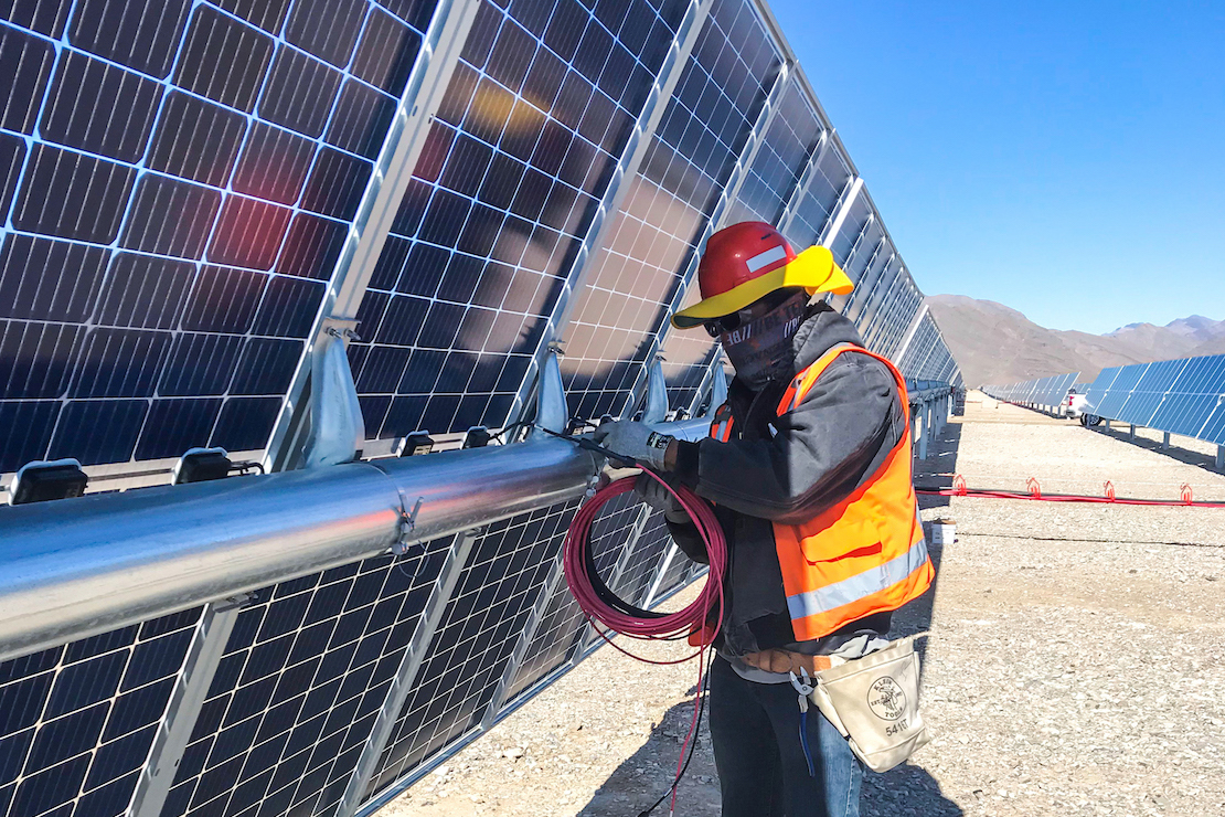 Man setting up BLA parallel harness on solar panels for MGM project