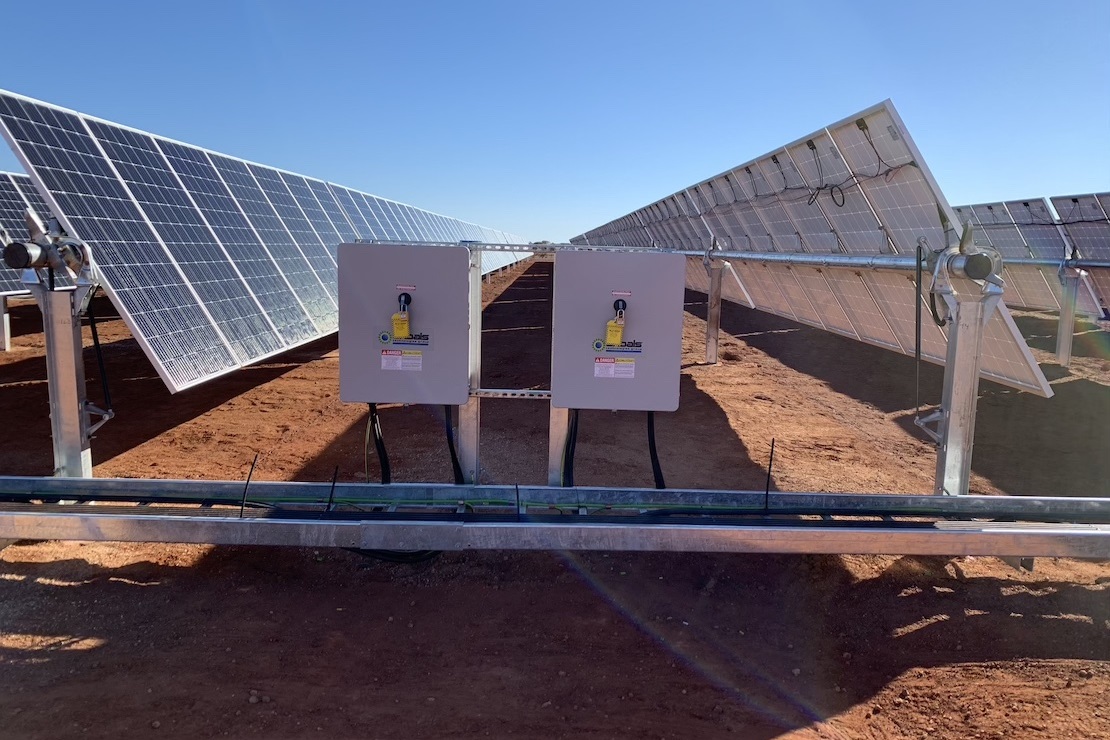Two Shoals disconnect boxes installed in front of rows of solar panels